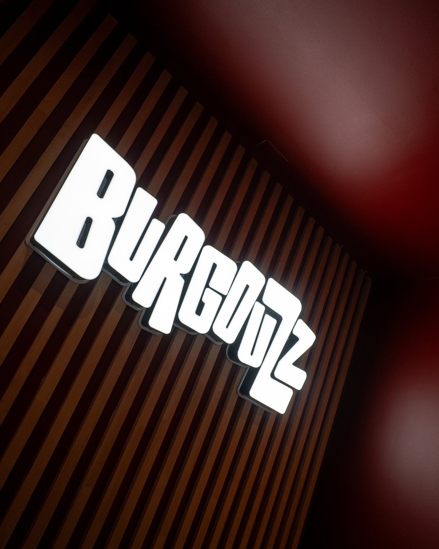 Enseigne Burgouzz lumineuse installée sur un mur en tasseaux de bois