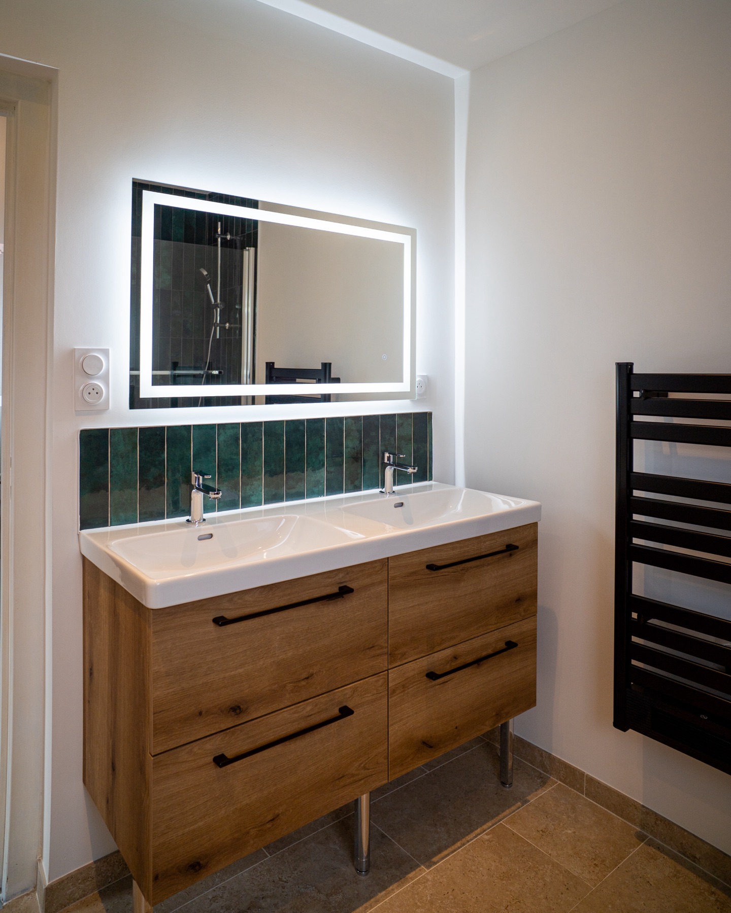 Meuble double vasque bois et miroir lumineux dans la salle de bain rénovée
