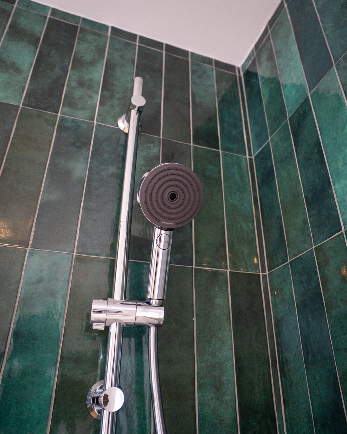 Douchette et carrelage vert profond dans l’espace bain